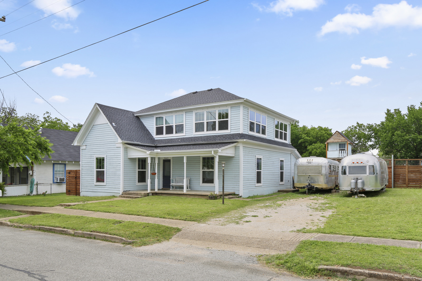 A pale blue two-story heritage home with a white-trimmed front porch and gabled roof on Oak Street in Frisco, Texas